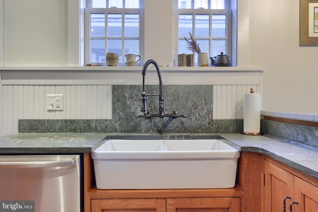 kitchen with a sink, dishwasher, and brown cabinetry