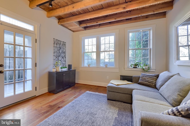 living area featuring radiator, baseboards, beamed ceiling, wooden ceiling, and wood-type flooring