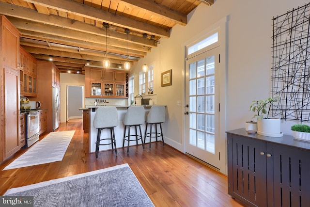 kitchen featuring a breakfast bar area, a peninsula, stainless steel appliances, and glass insert cabinets