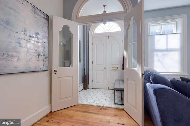 entrance foyer with a baseboard radiator, baseboards, and light wood-style flooring