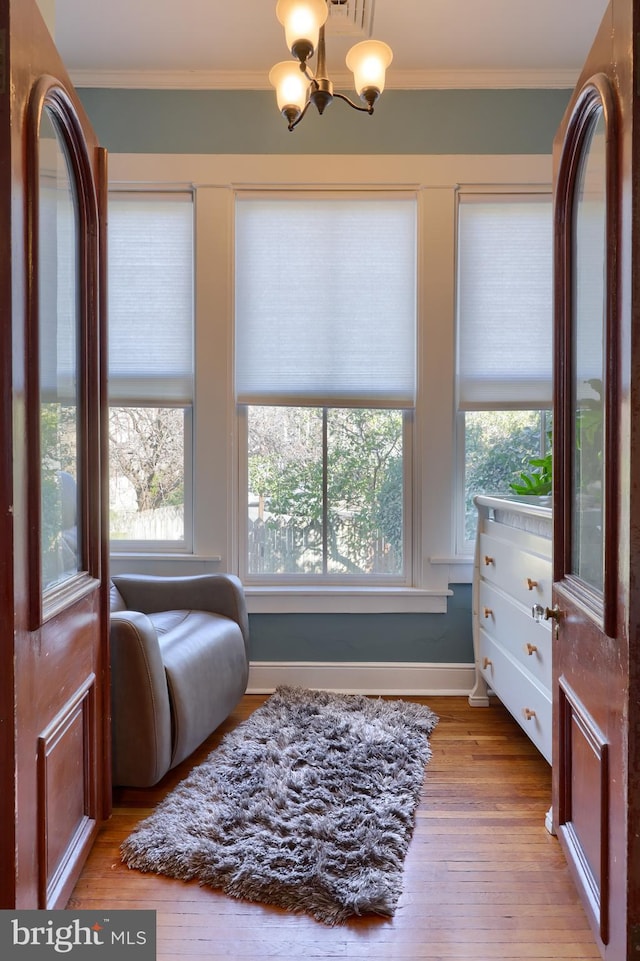 sitting room featuring an inviting chandelier, crown molding, and wood finished floors