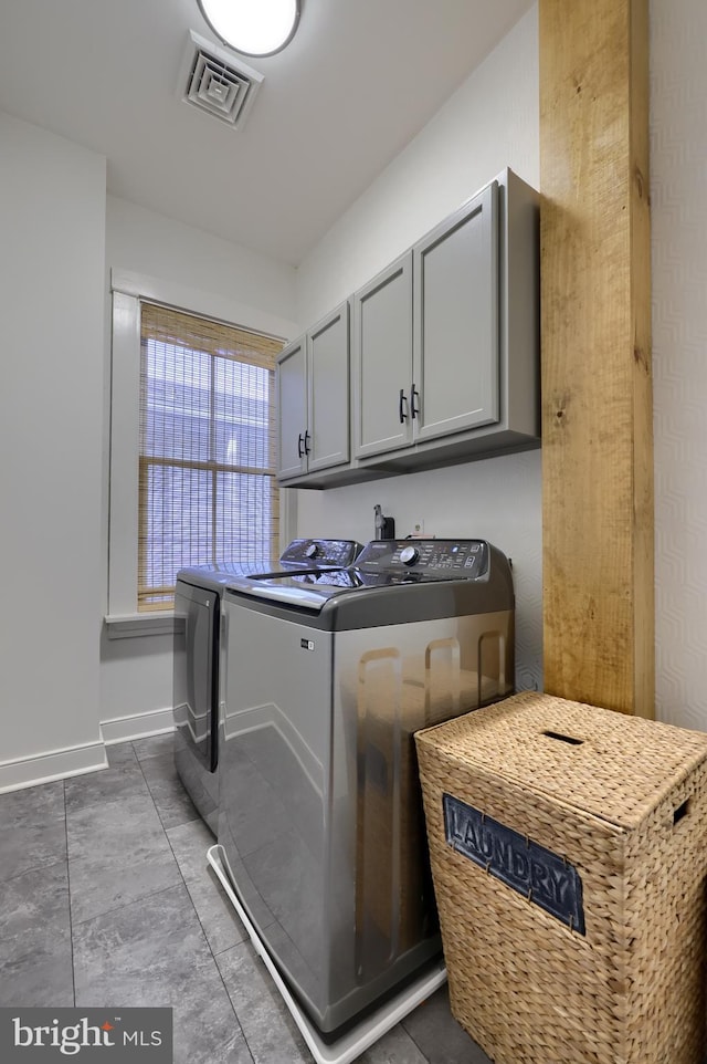 clothes washing area with washing machine and dryer, cabinet space, baseboards, and visible vents