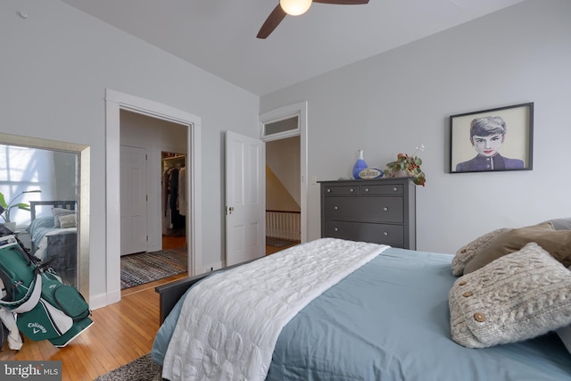 bedroom with a ceiling fan, a spacious closet, and wood finished floors