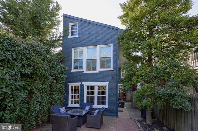 back of house featuring a patio, brick siding, outdoor lounge area, and fence