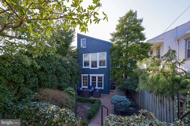 view of front of property featuring a patio area, fence, and brick siding