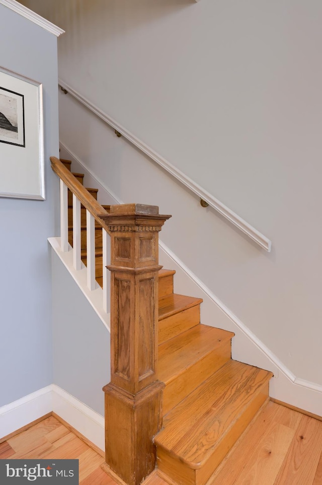 stairway with wood finished floors and baseboards