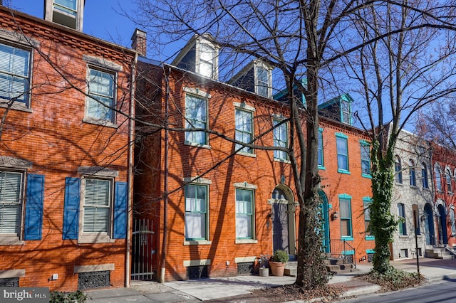 view of front of home featuring brick siding and a chimney