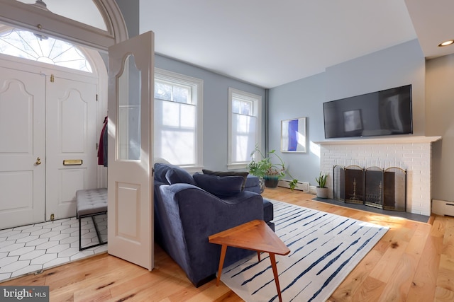 living area with a wealth of natural light, a brick fireplace, and light wood-type flooring