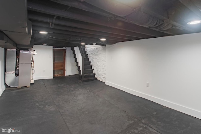 basement featuring heating unit, stairs, and baseboards