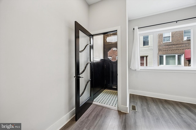 doorway with wood finished floors, visible vents, and baseboards