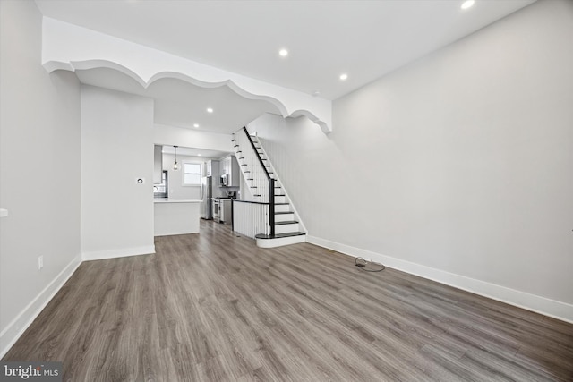 unfurnished living room with stairs, recessed lighting, wood finished floors, and baseboards