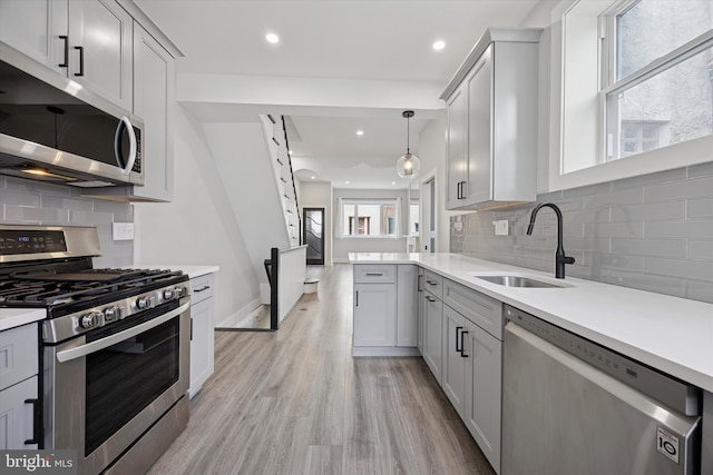 kitchen with appliances with stainless steel finishes, light countertops, light wood-style floors, a sink, and recessed lighting