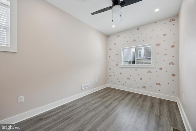 spare room featuring lofted ceiling, wallpapered walls, baseboards, and wood finished floors