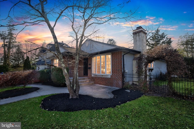 exterior space with driveway, brick siding, fence, and a chimney