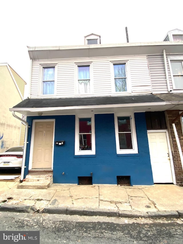 townhome / multi-family property with a porch and brick siding