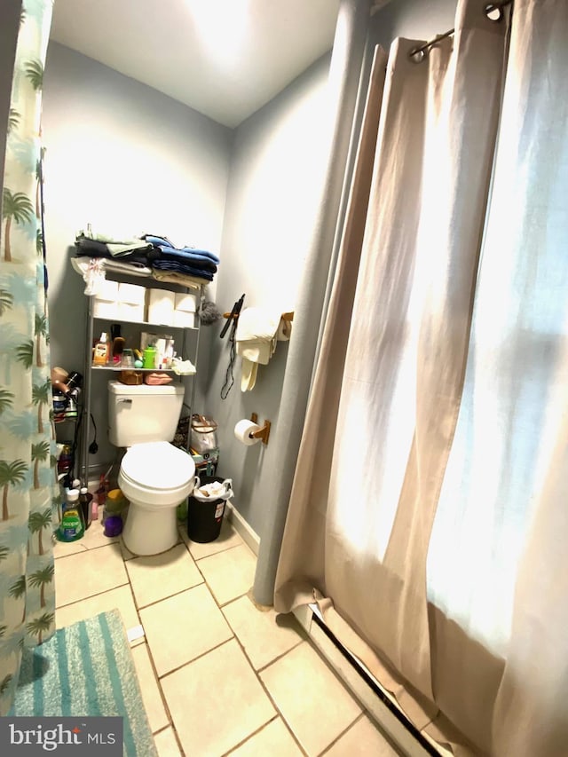 bathroom featuring baseboards, a shower with shower curtain, toilet, and tile patterned floors