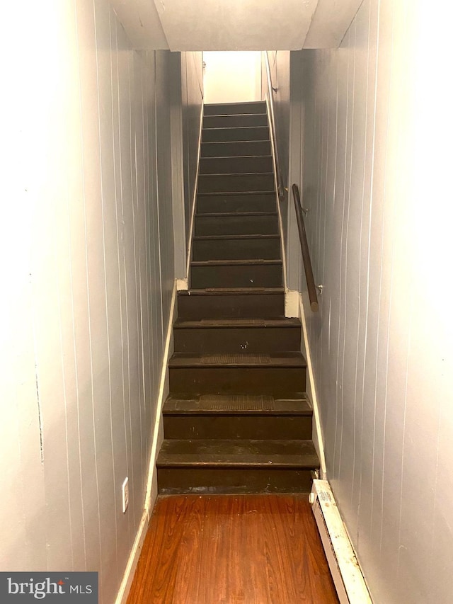 staircase with wood walls and wood finished floors