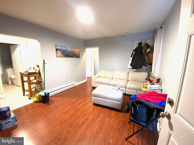 living room featuring a baseboard radiator, visible vents, baseboards, and wood finished floors