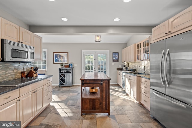 kitchen featuring stone tile floors, a sink, baseboards, french doors, and appliances with stainless steel finishes