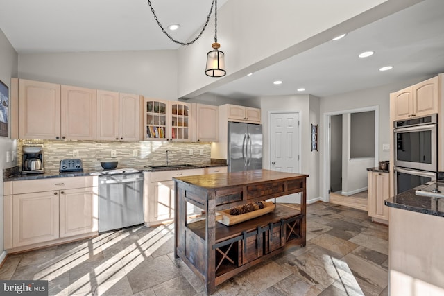 kitchen featuring a sink, vaulted ceiling, appliances with stainless steel finishes, decorative backsplash, and glass insert cabinets