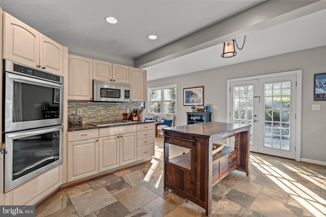 kitchen with stainless steel appliances, dark countertops, stone tile flooring, and backsplash