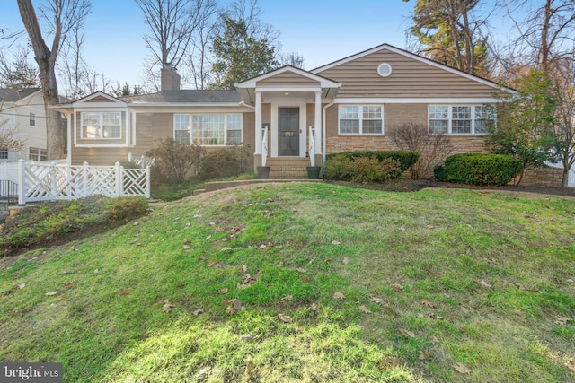 view of front of home featuring a front yard, brick siding, fence, and a chimney