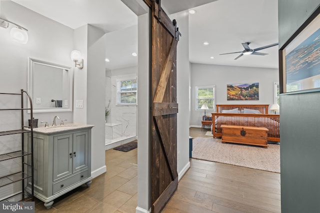 full bath featuring a ceiling fan, vanity, wood finished floors, baseboards, and walk in shower