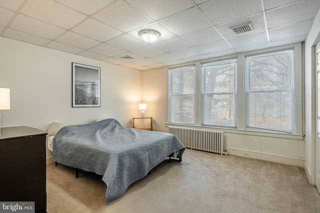 bedroom featuring carpet floors, radiator heating unit, visible vents, and a drop ceiling