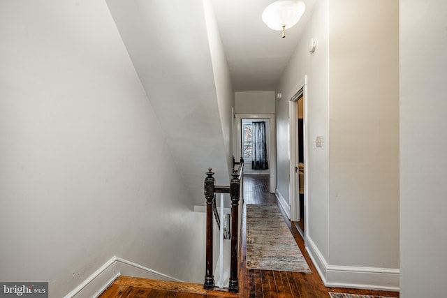 hall with wood finished floors, an upstairs landing, and baseboards