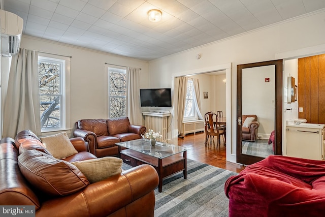 living room featuring crown molding, a wall mounted air conditioner, plenty of natural light, and wood finished floors