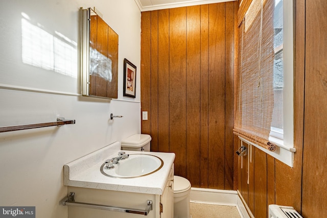 half bath with toilet, a baseboard heating unit, and vanity