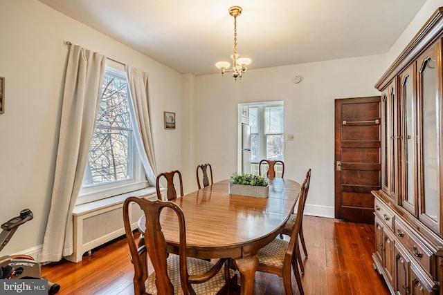 dining room with dark wood-style floors, baseboards, a chandelier, and radiator