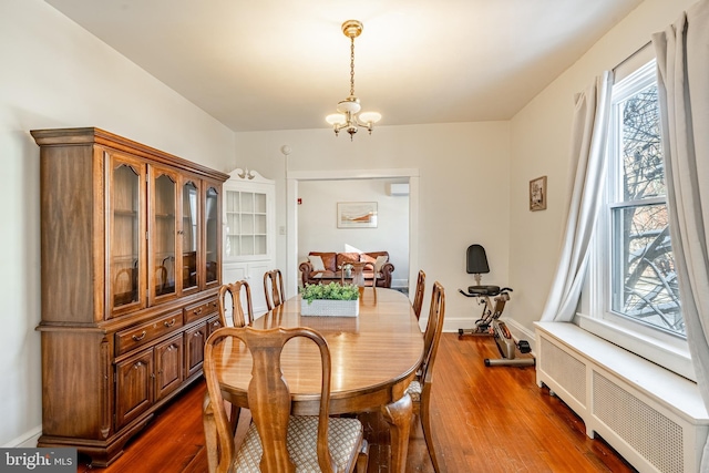 dining room with baseboards, radiator heating unit, dark wood finished floors, and an inviting chandelier