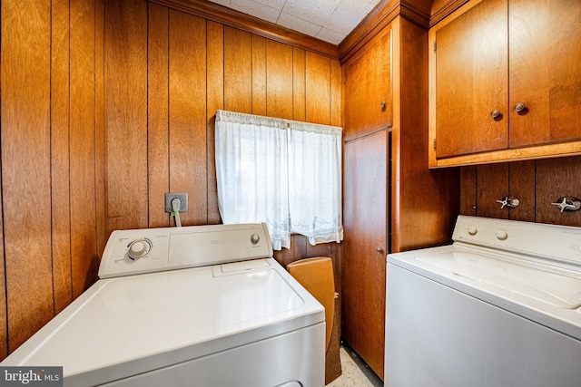 washroom featuring cabinet space, independent washer and dryer, and wood walls