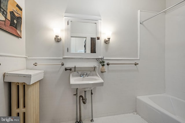 full bath with a sink, a wainscoted wall, and tile walls