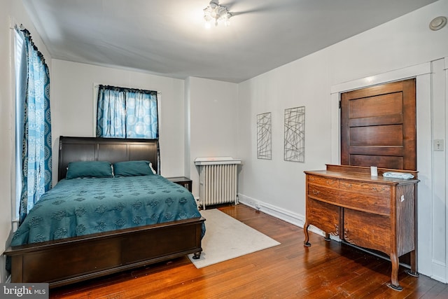 bedroom with radiator heating unit, hardwood / wood-style flooring, and baseboards