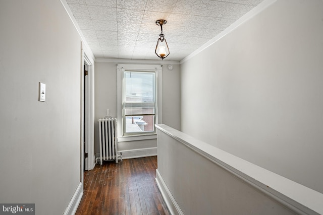 corridor featuring dark wood-style flooring, an upstairs landing, baseboards, ornamental molding, and radiator