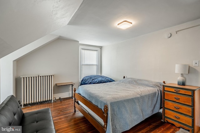 bedroom featuring lofted ceiling, radiator heating unit, and wood finished floors