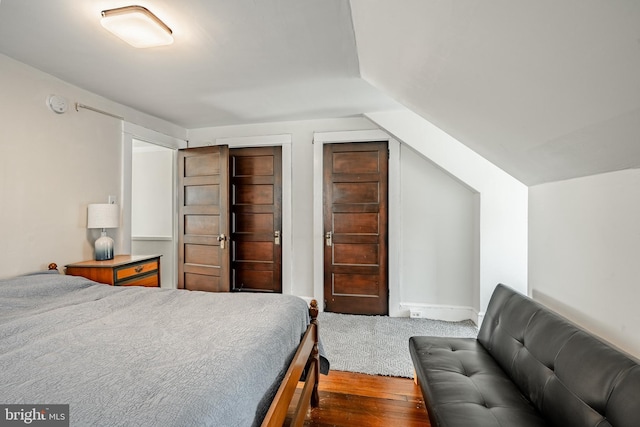 bedroom with vaulted ceiling and wood finished floors