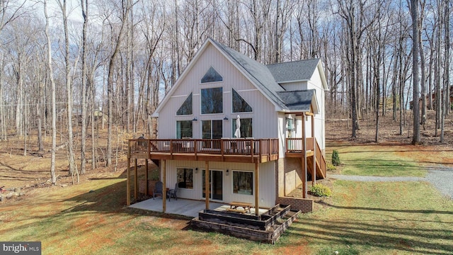 rear view of property featuring a patio, a shingled roof, a lawn, and a wooden deck