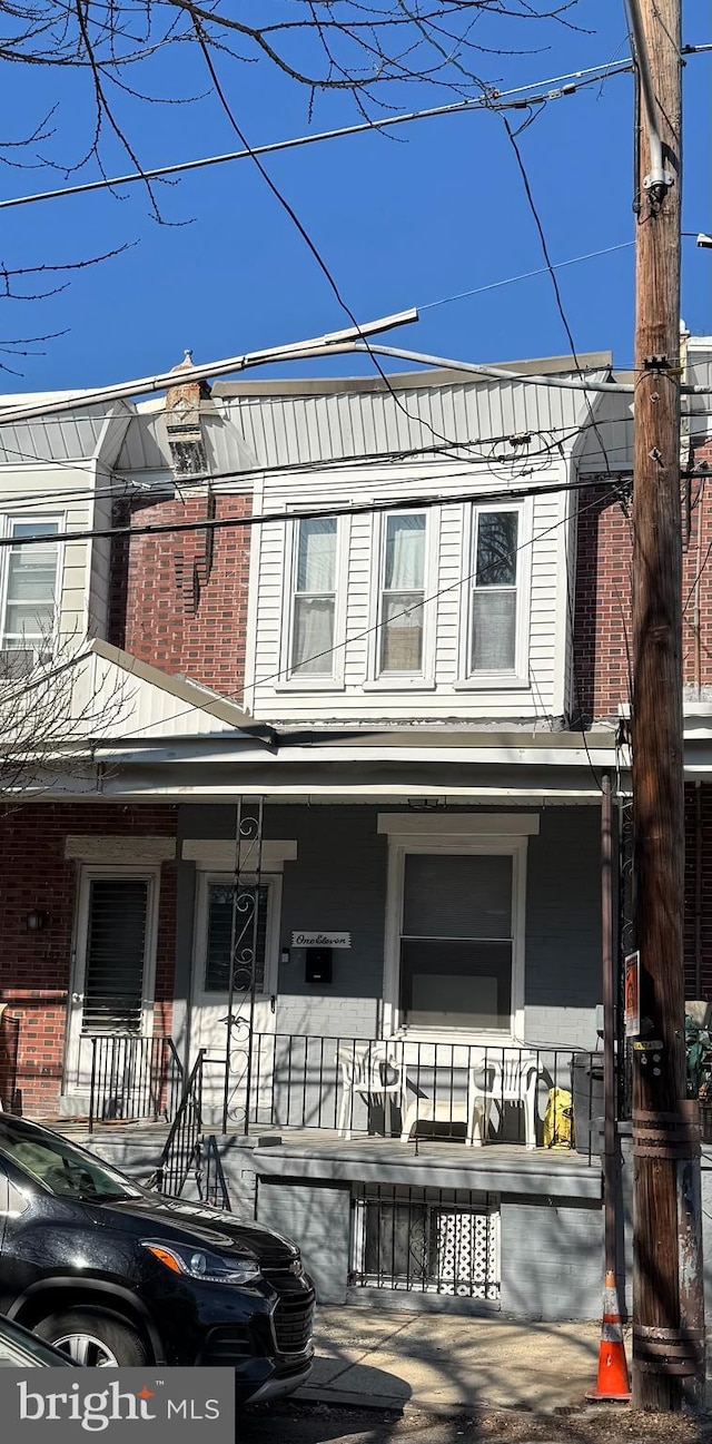 multi unit property featuring covered porch and brick siding