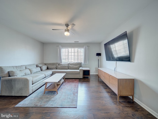 living room featuring baseboards, a ceiling fan, and dark wood-style flooring