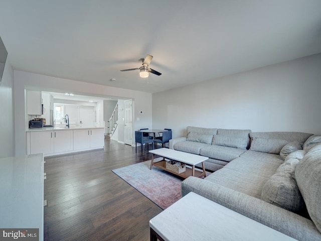 living area featuring stairs, ceiling fan, and dark wood finished floors