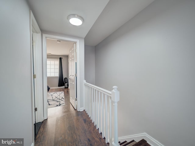 hallway featuring baseboards, an upstairs landing, and wood finished floors