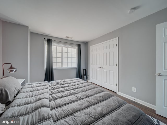 bedroom featuring dark wood-style floors, baseboards, visible vents, and a closet