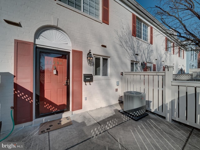 doorway to property with central AC and brick siding