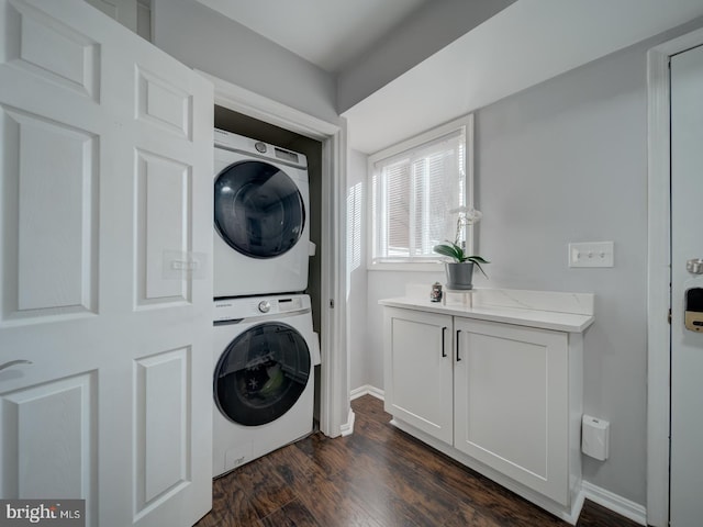 laundry room with dark wood-style floors, baseboards, laundry area, and stacked washer / dryer