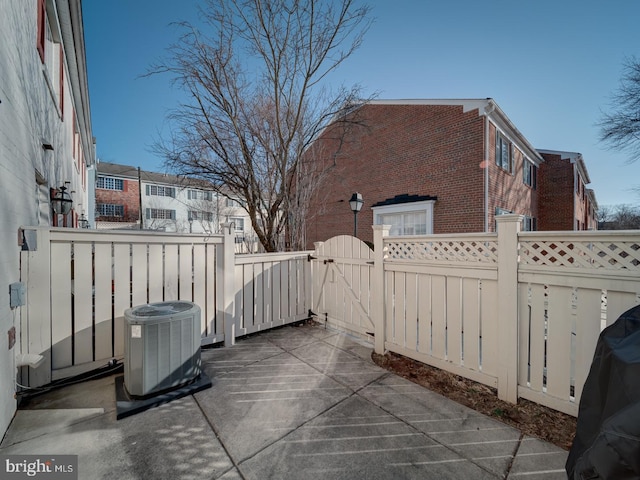 view of patio featuring central AC, fence, and a gate