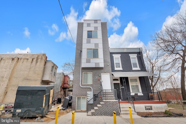 townhome / multi-family property featuring covered porch and brick siding