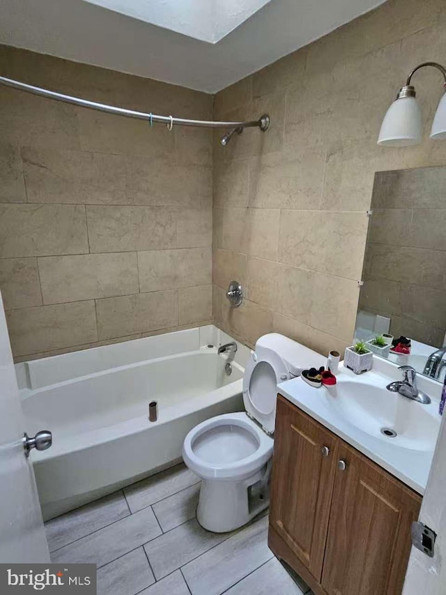 bathroom featuring toilet, vanity, tile walls, and bathing tub / shower combination